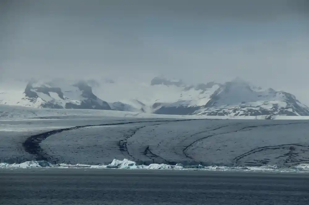 Black sand beach with glacier and snow mountains