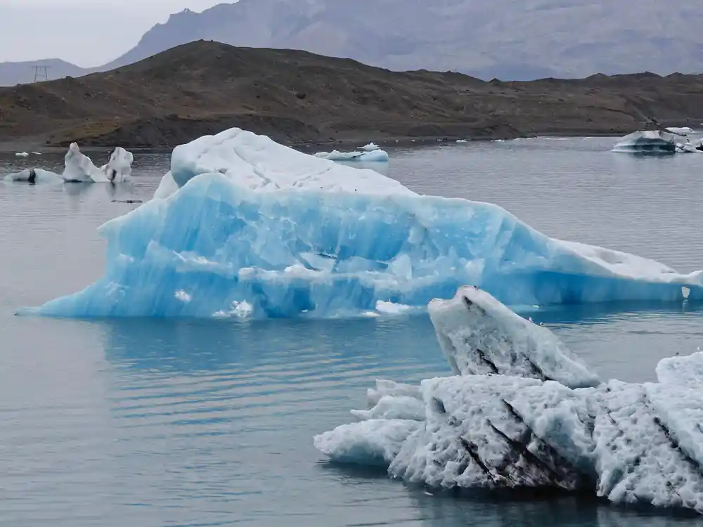 Blue ice formations in glacial lake with mountains