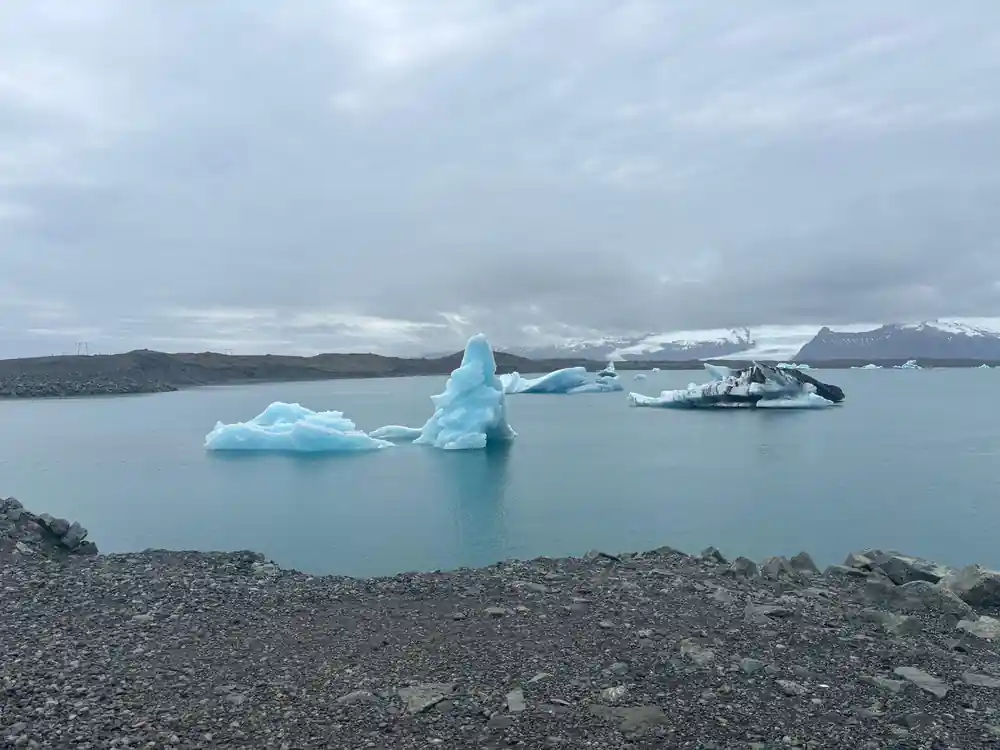 Blue icebergs floating in glacial lake with boat