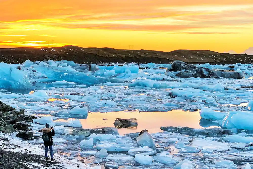 Blue icebergs floating in water at golden sunset