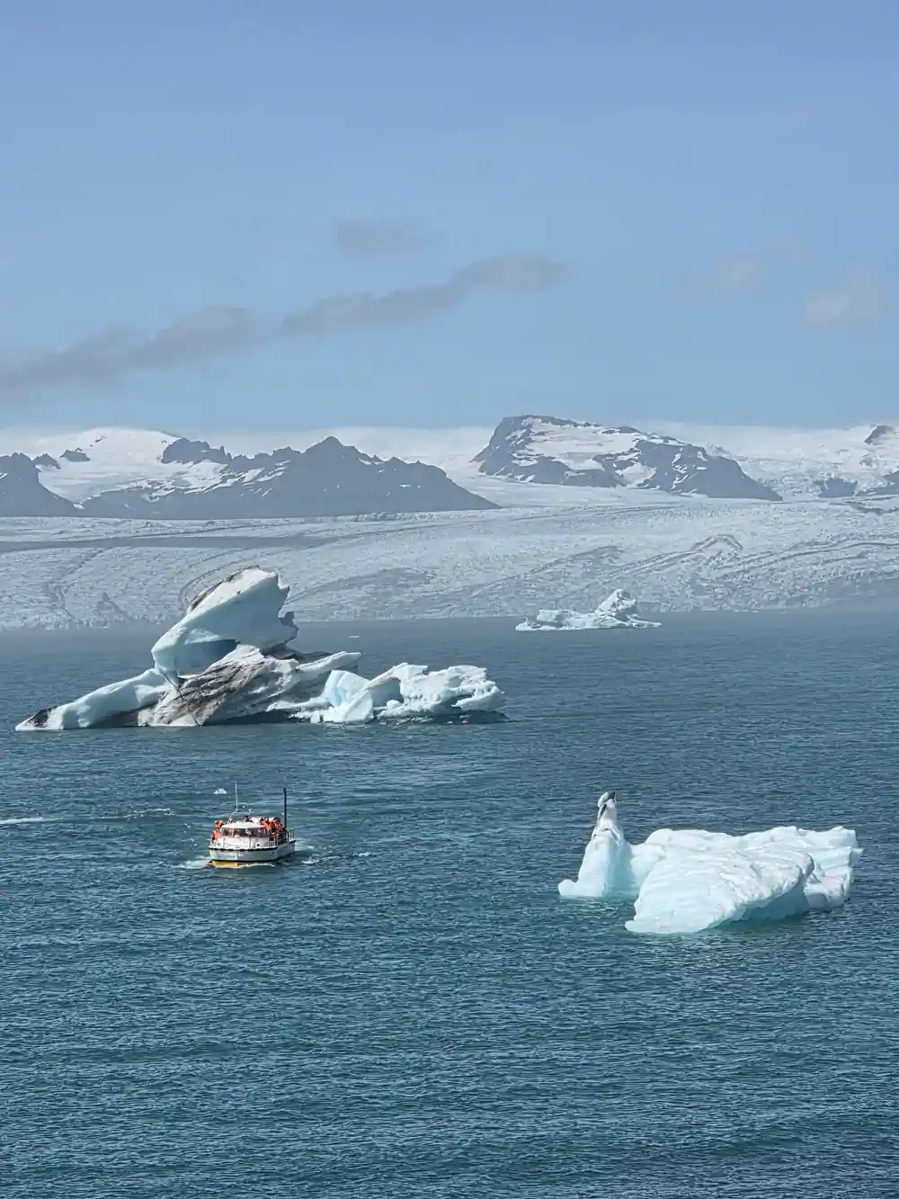 Boat near large icebergs in glacier lagoon