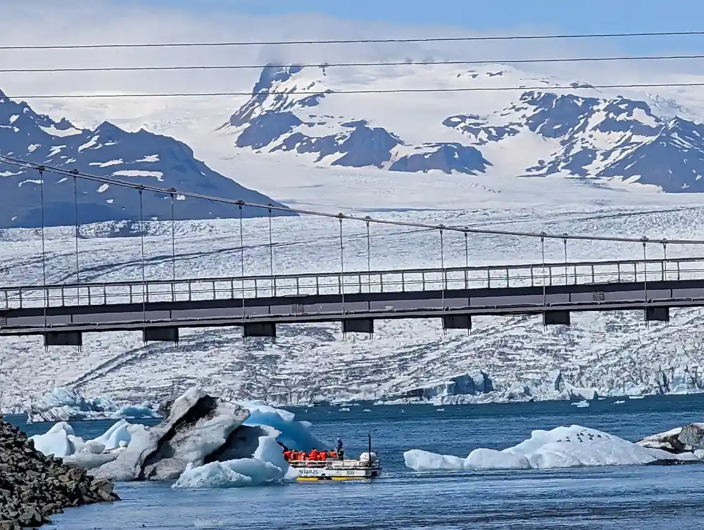 Glacier lagoon with icebergs, bridge and snow-capped peaks