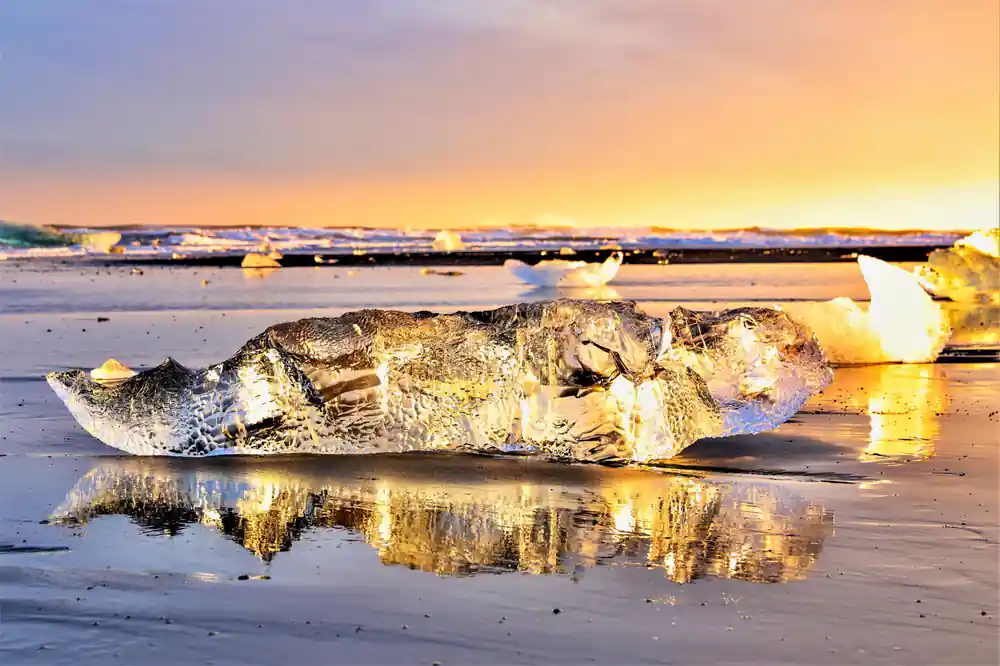 Ice chunk on beach at sunrise with golden light