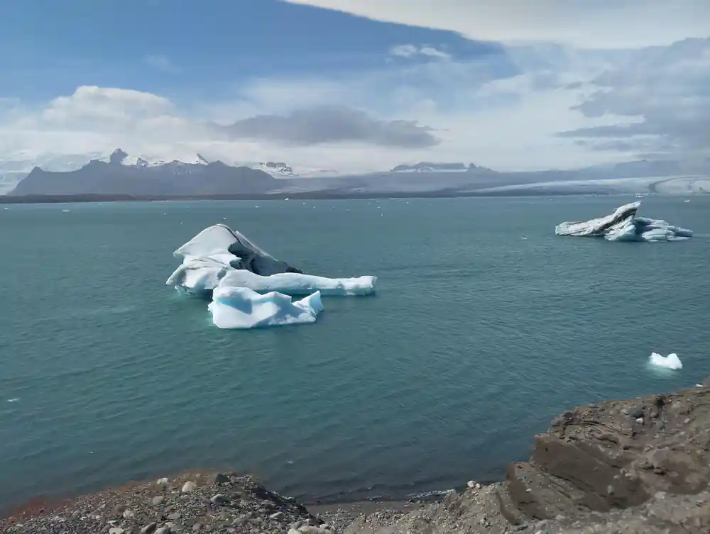 Icebergs floating in turquoise glacial lake with mountains