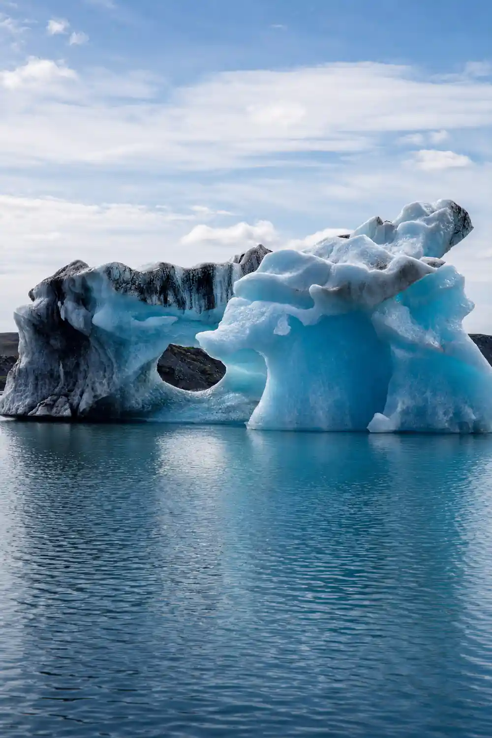 Large blue iceberg with dark rock hole floating