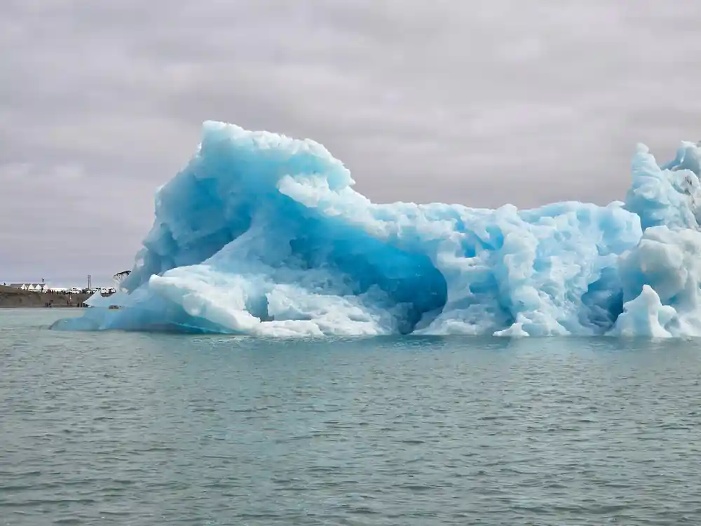 Large blue iceberg floating in lagoon water