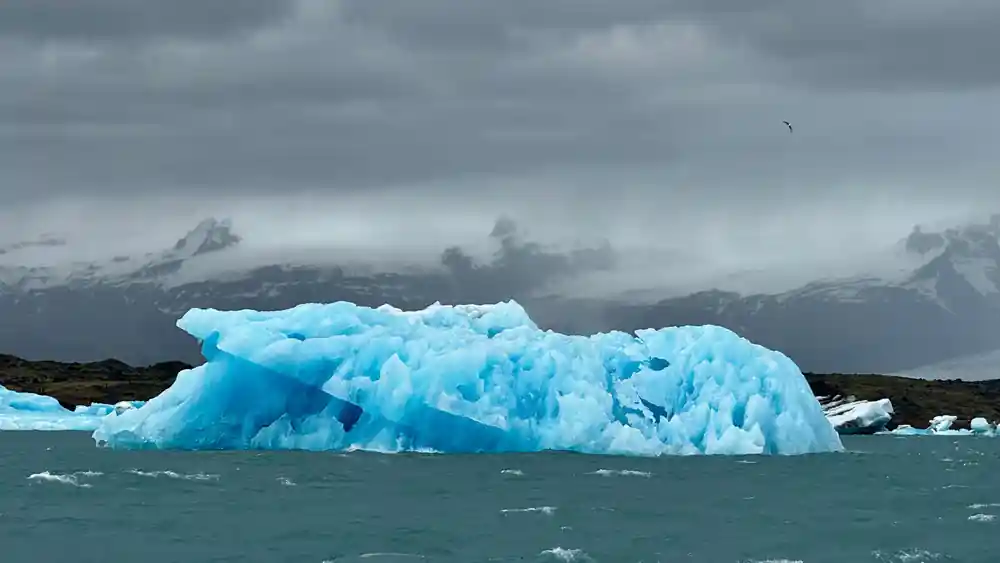 Large blue iceberg floating in turquoise glacial water