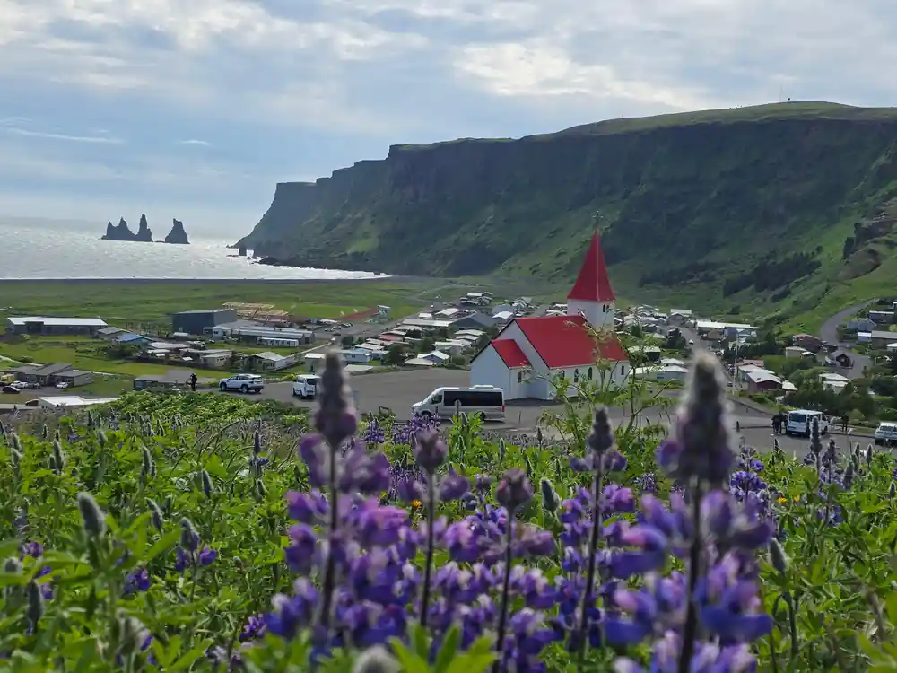 Red church with purple flowers and coastal cliffs