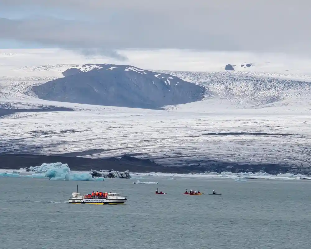 Snowy volcanic crater with boats and icebergs in foreground