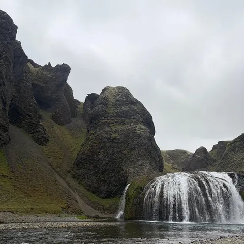 The Stjórnarfoss waterfall below green cliffs
