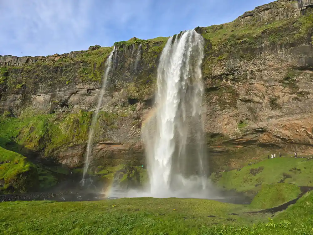 Tall waterfall from cliff with green moss and grass