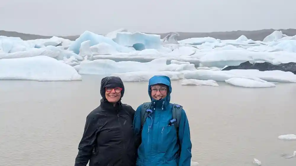 Two people standing before glacial ice lagoon