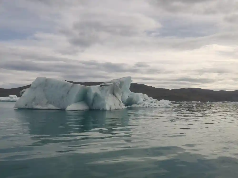 White iceberg with dark band floating in still water