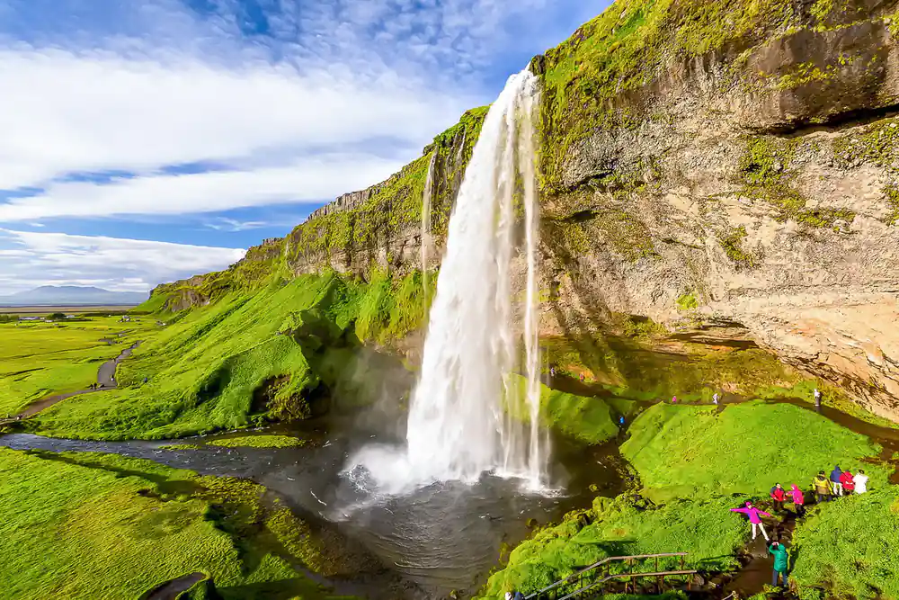 Wide waterfall with lush green slope and river