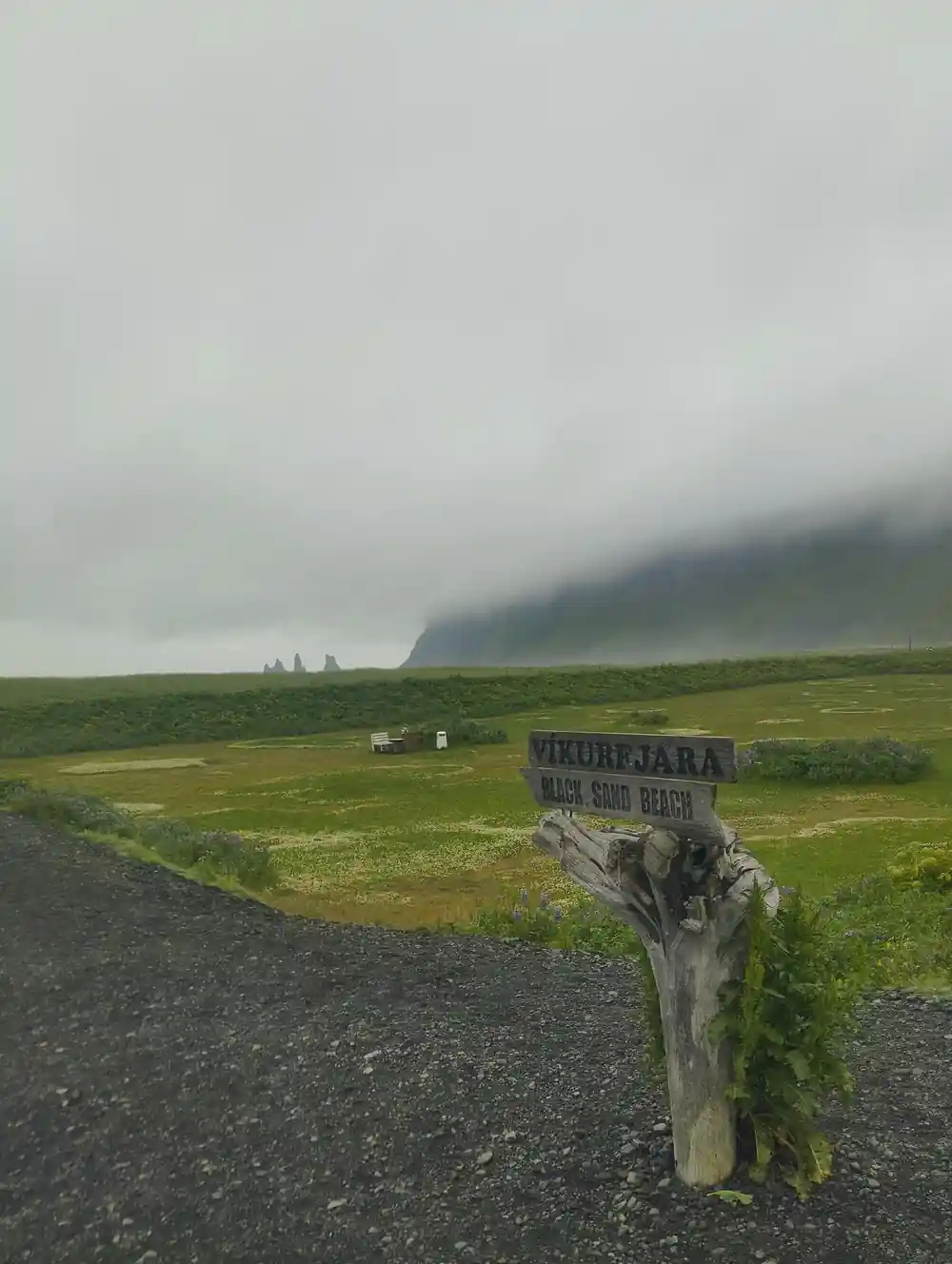 Wooden sign on road overlooking misty green valley